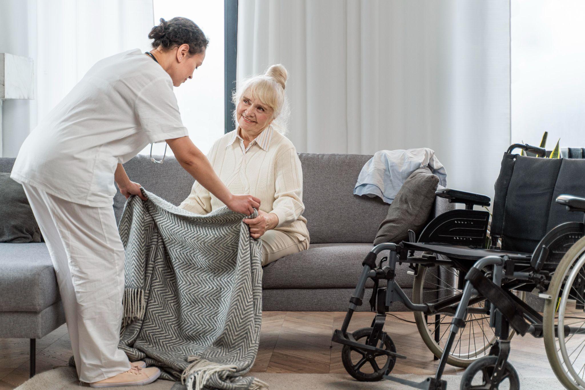 caregiver helping an elderly woman settle comfortably at home while assisting with daily routines