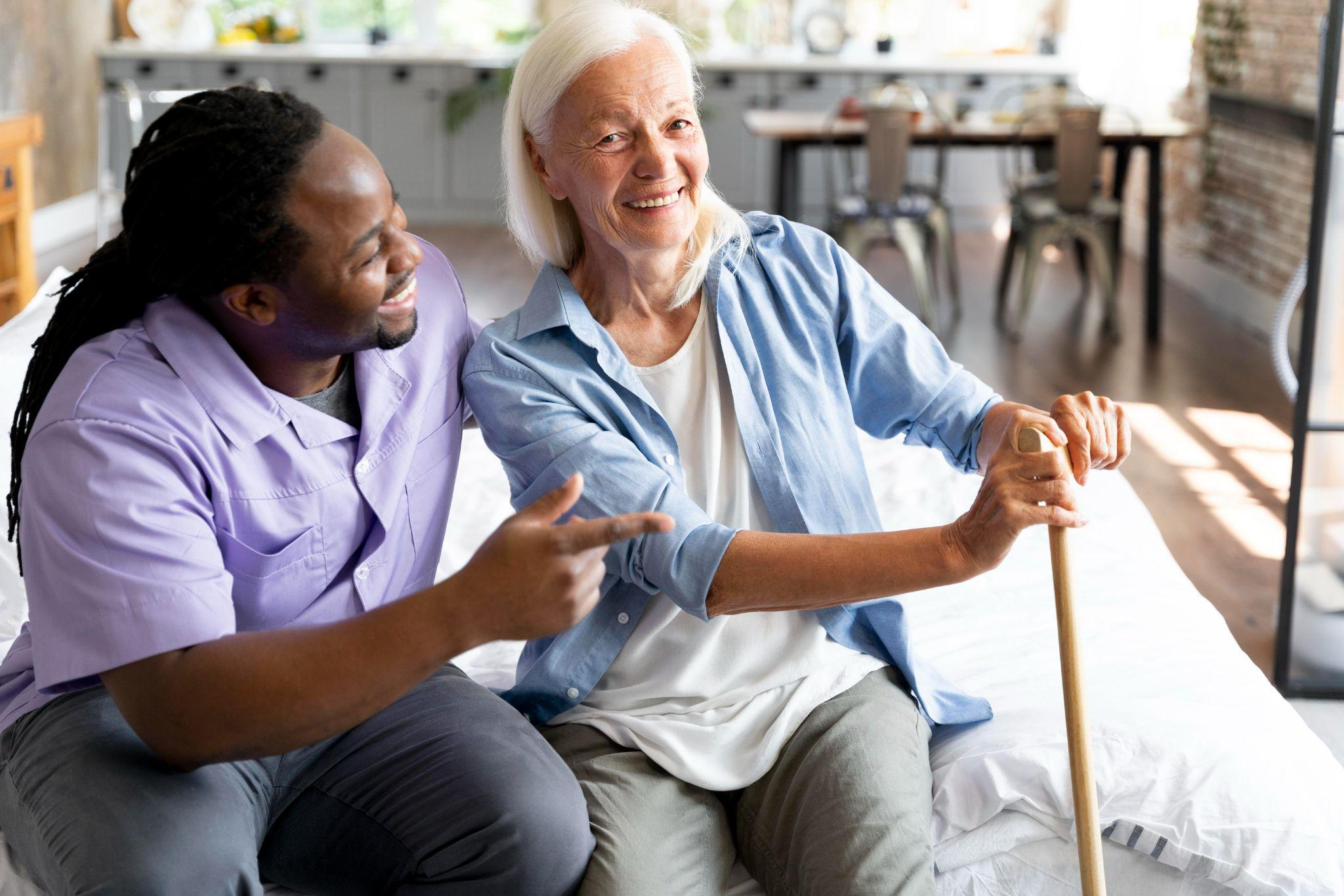 caregiver sitting beside a senior woman at home offering support and conversation after mobility changes