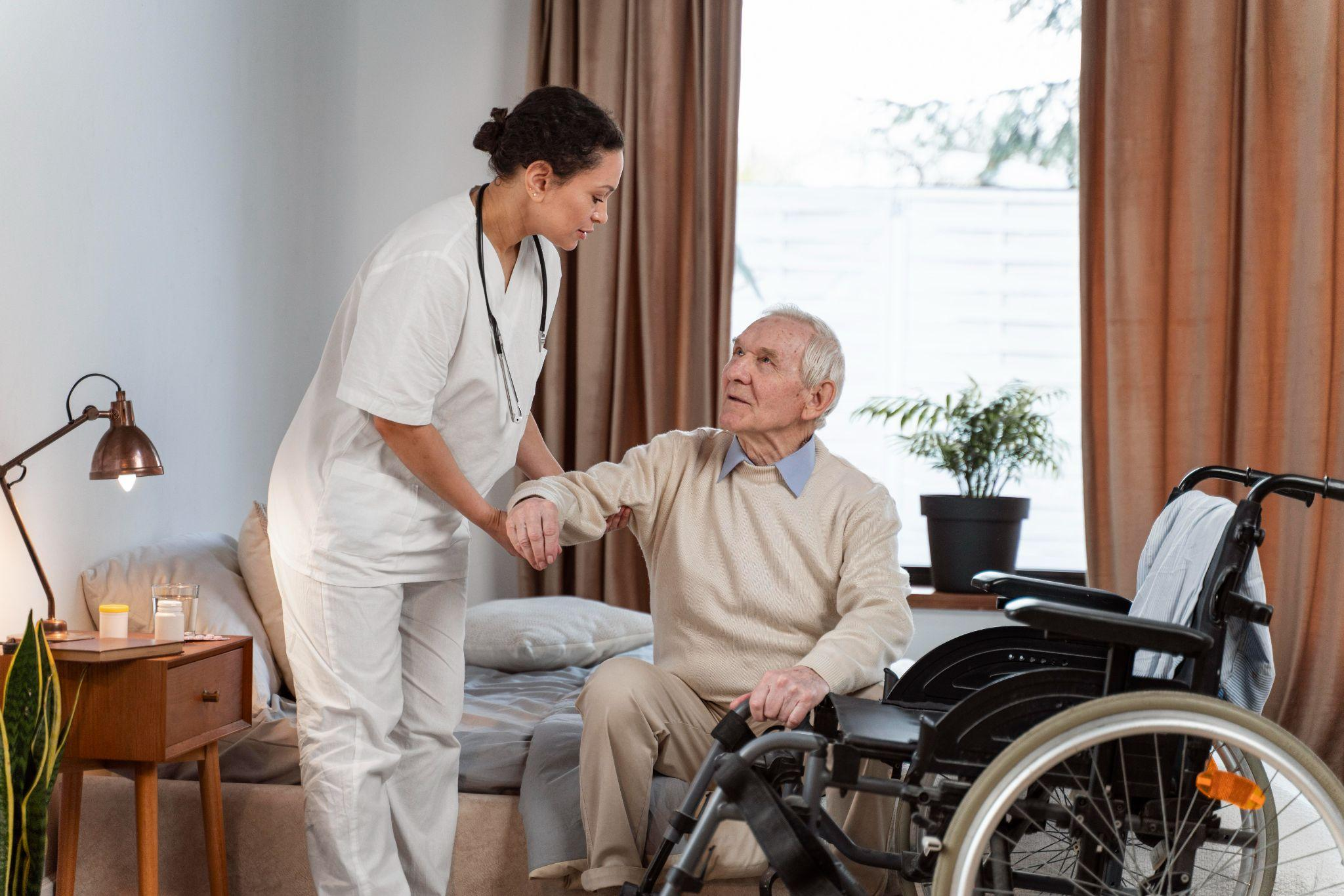 caregiver assisting an elderly man with mobility in a bedroom during recovery at home